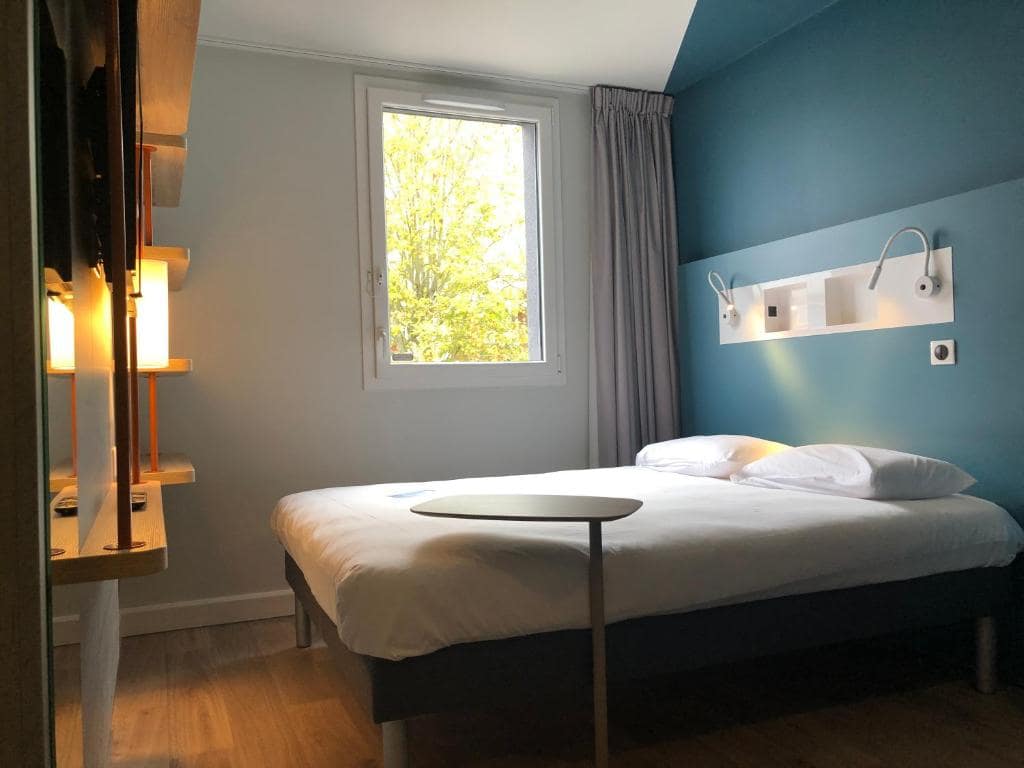 A hotel room with blue walls and a bed.