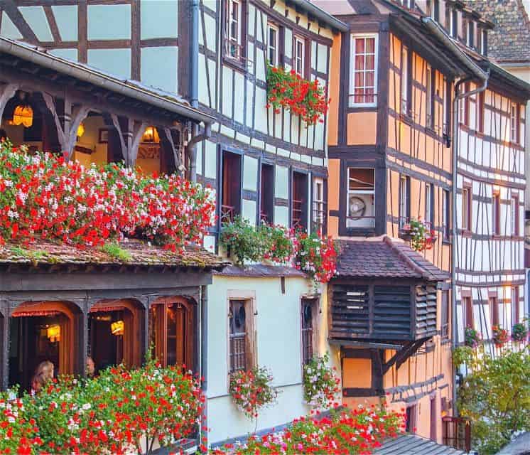 A row of houses with flower-filled balconies, perfect for a peaceful retreat or wine tours from Paris.