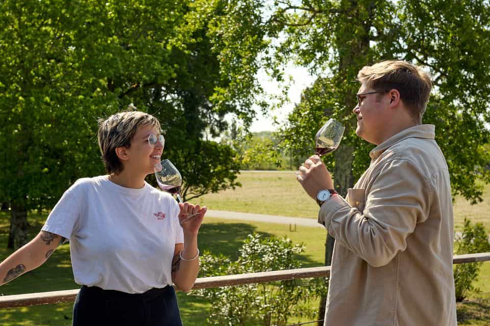 A couple enjoying wine in a vineyard during their wine tour from Paris.