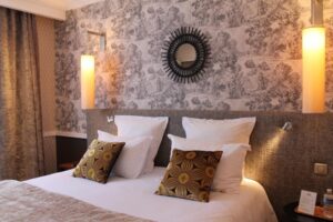 A bed in a hotel room with floral wallpaper in Chalons en Champagne.