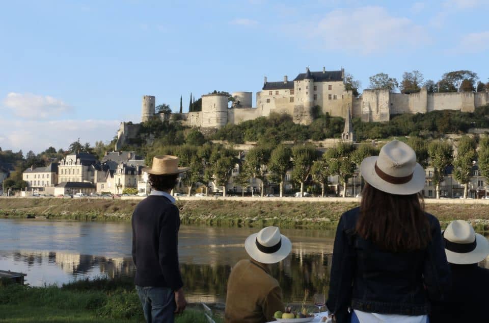 A group of people are enjoying wine tours from Paris with a castle in the background.