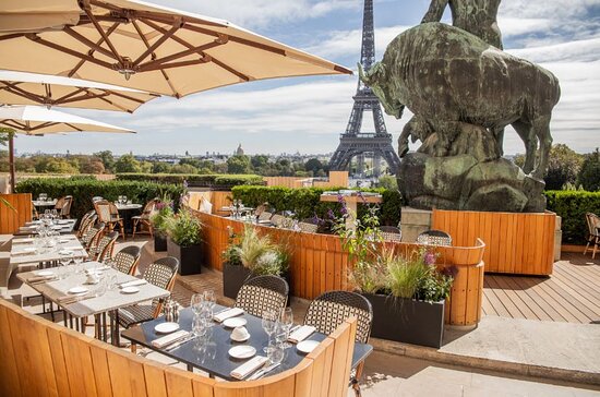 The Eiffel Tower Restaurant features tables and chairs with the iconic tower in the background.