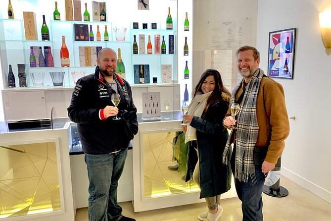 Three people standing in front of a display of wine bottles.