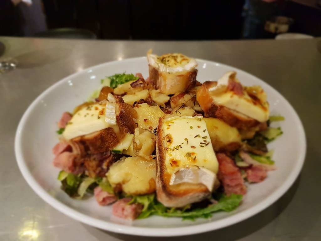 A plate with ham, cheese, and potatoes on it served at a restaurant in Reims.