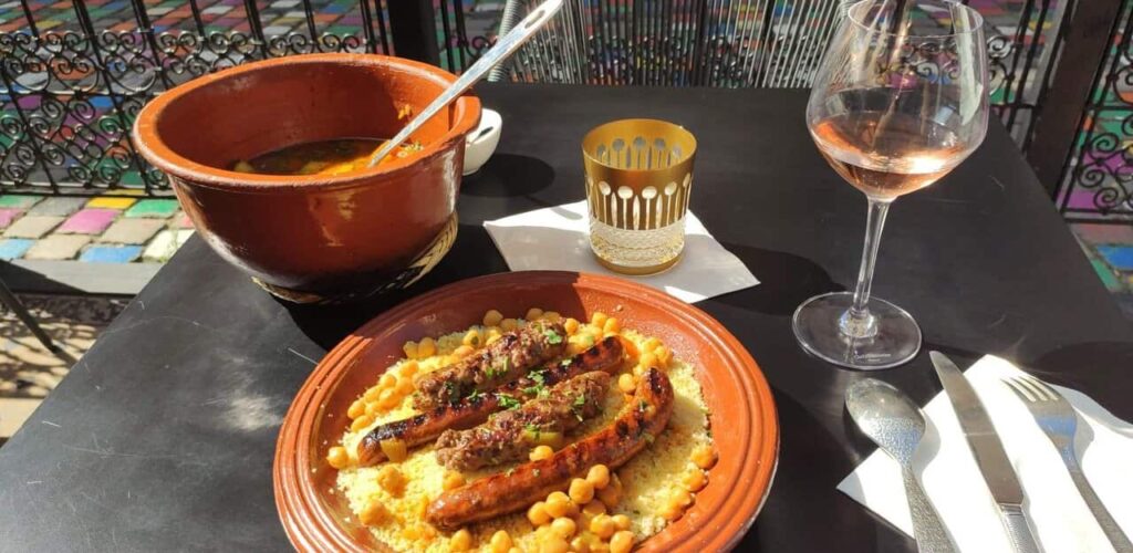 A plate of food on a table in a restaurant next to a glass of wine.