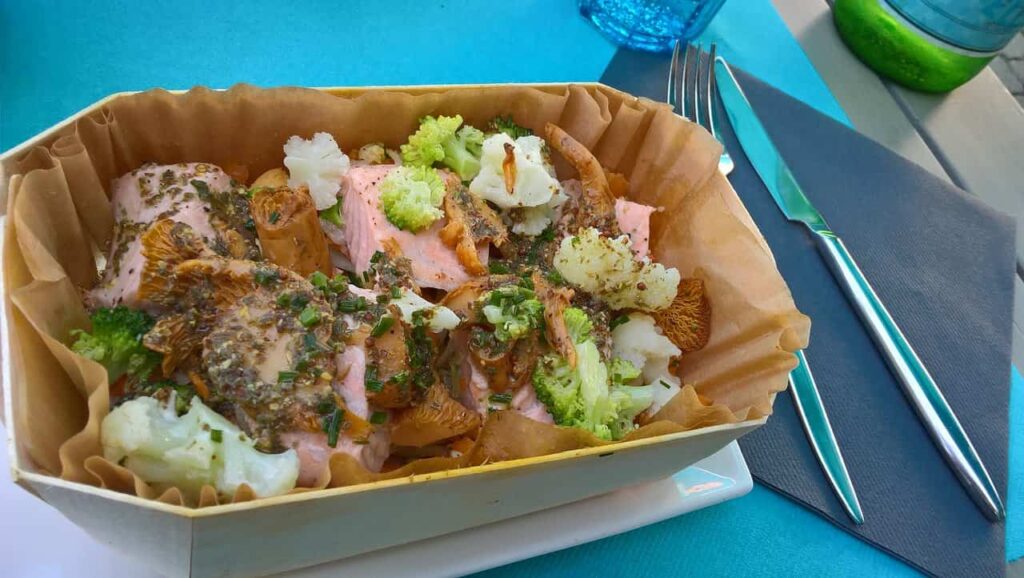 A box of food on a table at a restaurant in Reims with a fork.