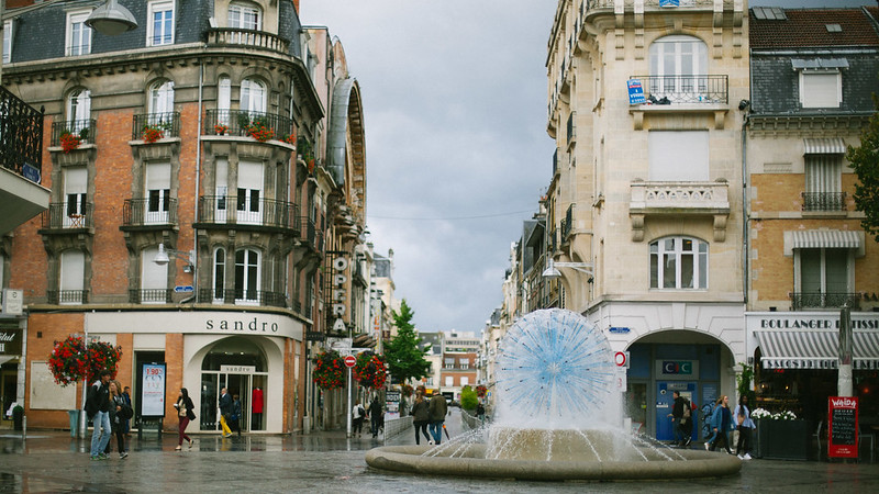 A Reims fountain in the middle of a bustling city.