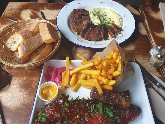 A plate of french fries and ribs at Troyes Restaurant, displayed on a wooden table.