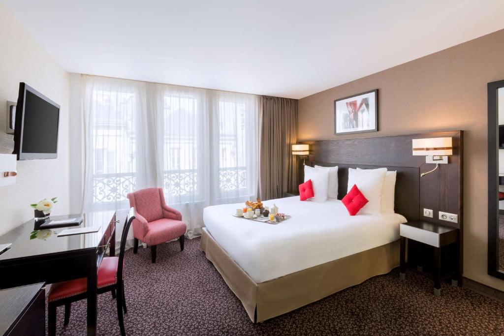 A hotel room with a bed, desk and chair.
