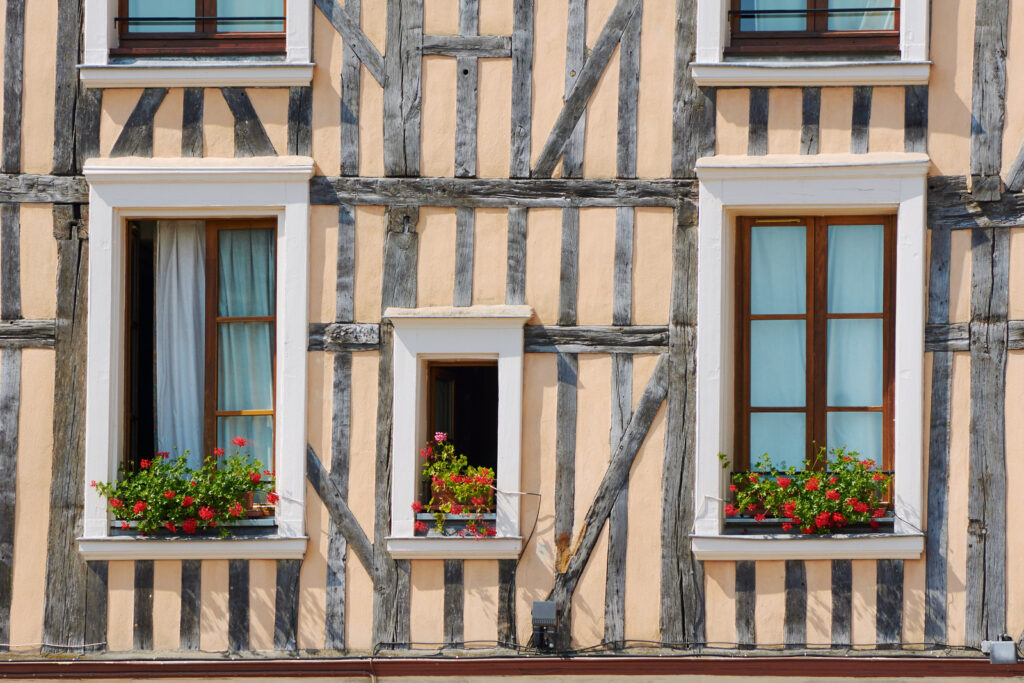 A Troyes Restaurant with wooden building featuring windows adorned with vibrant flowers.