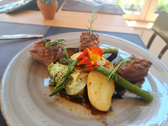 A plate with meat and vegetables on it at Troyes Restaurant.