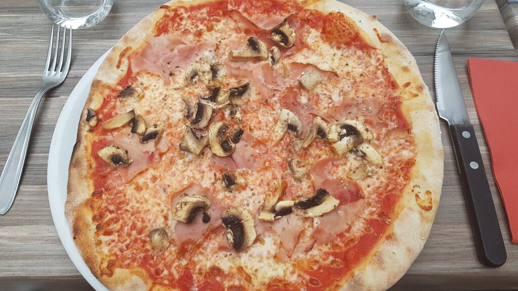 A pizza on a table with a knife and fork at Troyes Restaurant.
