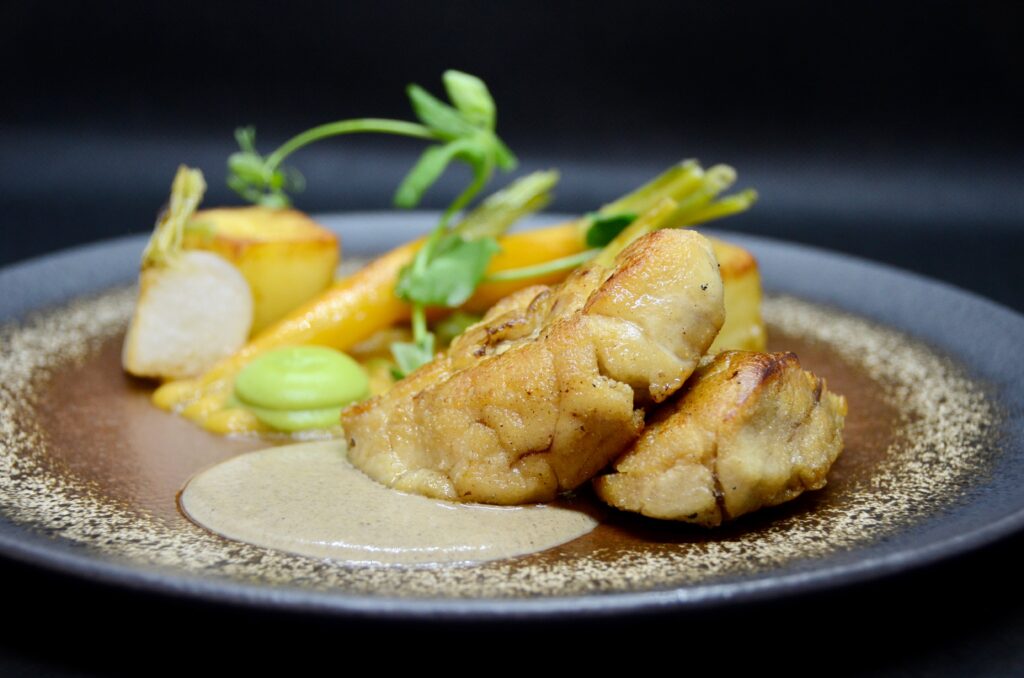 A plate with chicken and vegetables on it at Troyes Restaurant.