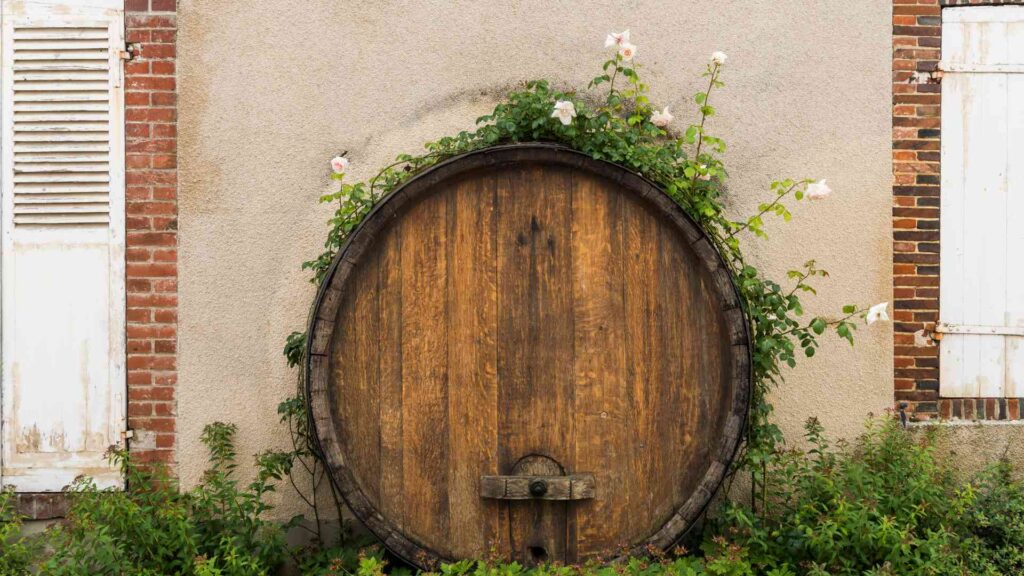 An old wooden wine barrel in front of a building.