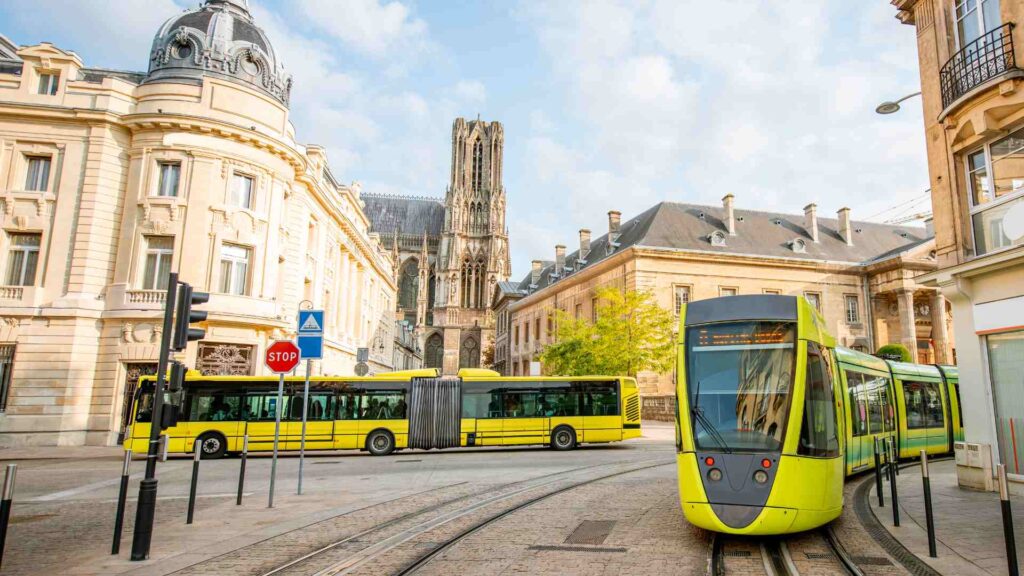 A yellow tram is driving down a city street.